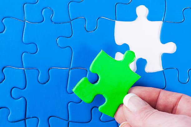 Close up of woman's hand placing missing piece in Jigsaw puzzle  signifying problem solving and decision making